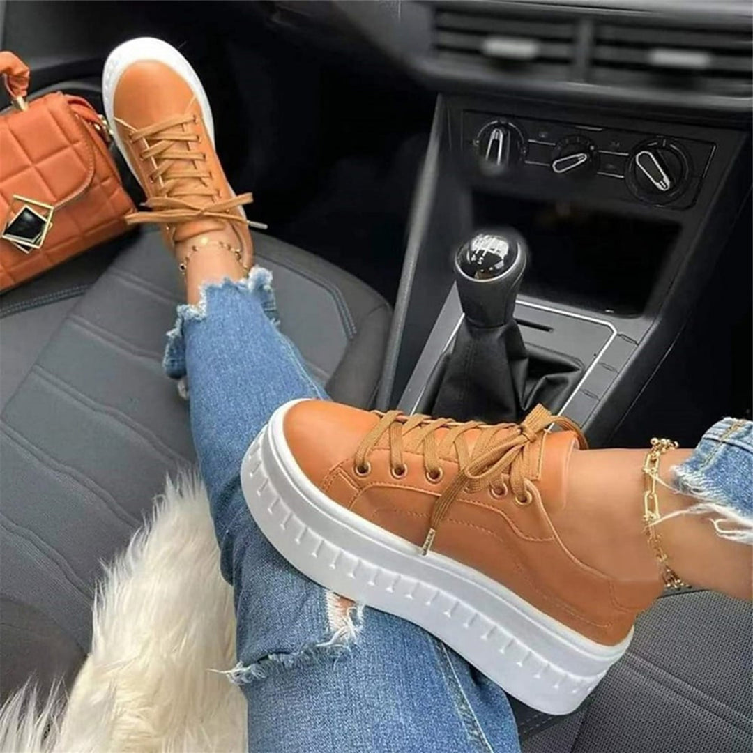 Buty Sportowe Damskie Na Platformie w kolorze brązowym z grubą białą podeszwą i sznurowaniem, noszone z jeansami