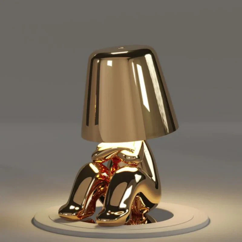 Lampa nocna LED z figurką w pozycji siedzącej i metalicznym wykończeniem