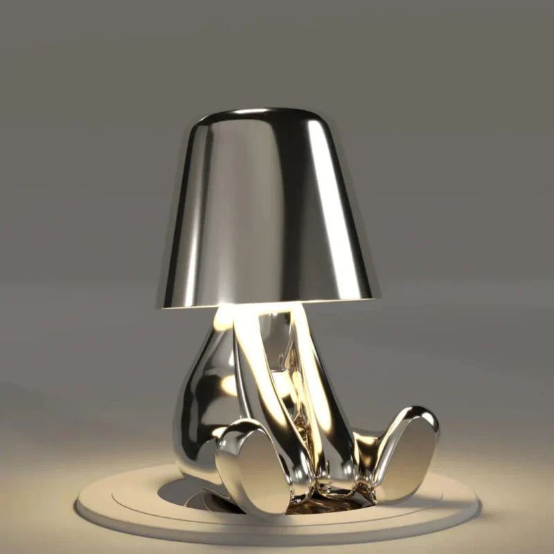 Designerska lampka stołowa z postacią ludzką i kloszem LED w srebrnym kolorze