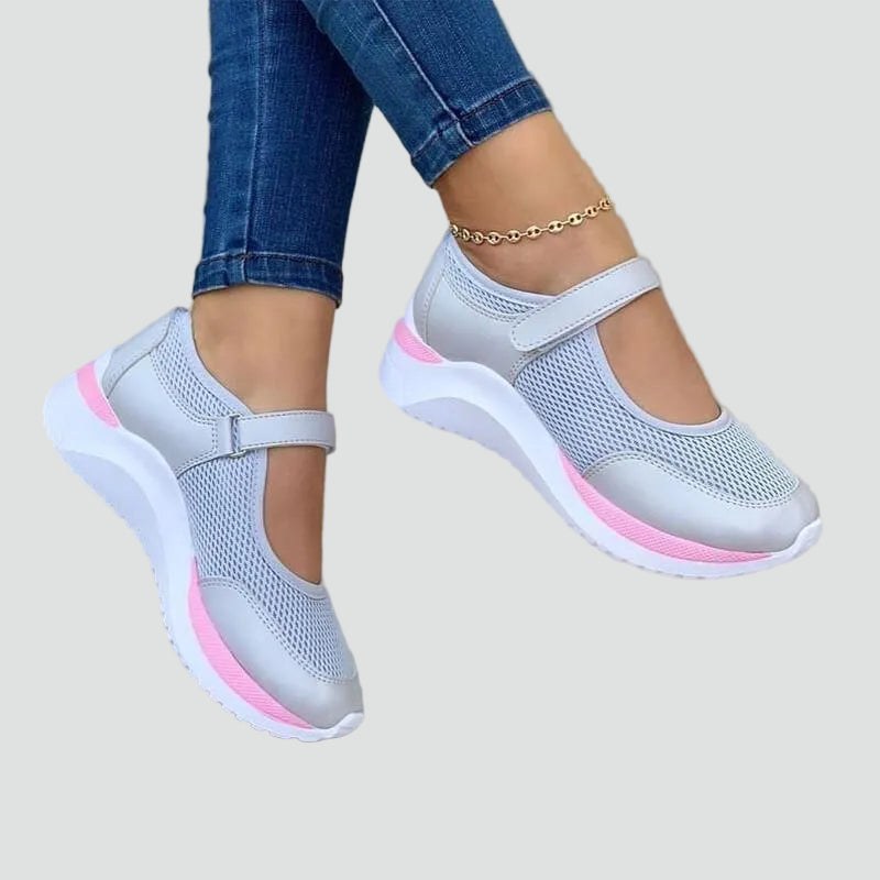 Sneakersy damskie siateczkowe na rzep w kolorze szarym z różową podeszwą noszone z dżinsami