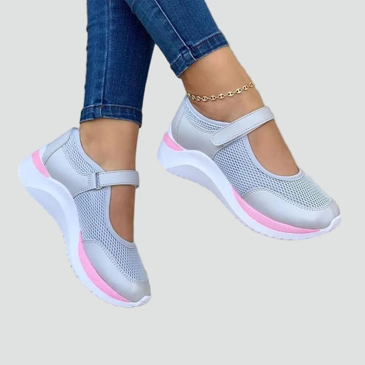 Sneakersy damskie siateczkowe na rzep w kolorze szarym z różową podeszwą noszone z dżinsami