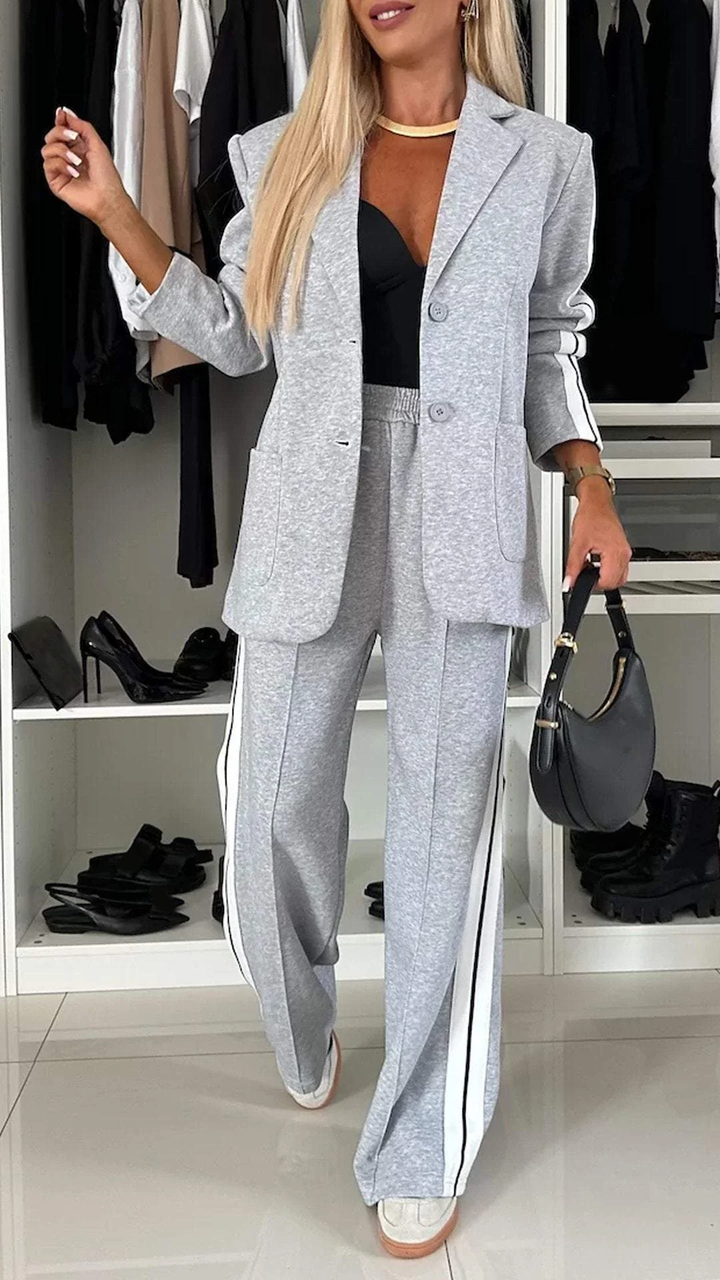 Kobiecy garnitur biurowy w stylu casual – szara marynarka i spodnie z lampasami na modelce