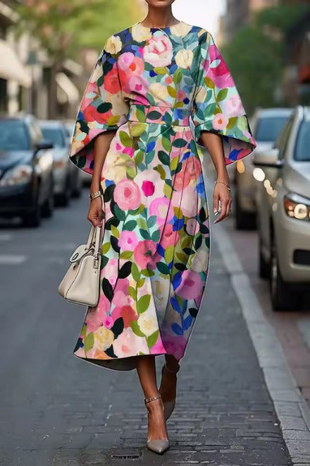 Sukienka midi w kolorowe kwiaty z szerokimi rękawami typu kimono i paskiem w talii na ulicy miejskiej